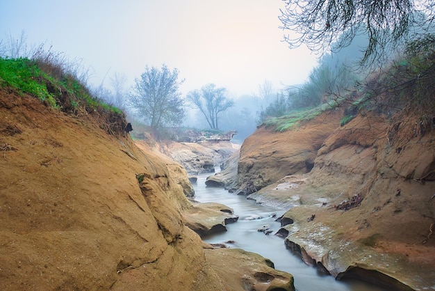 Arroyo de agua sedosa entre rocas en una brumosa mañana de invierno.