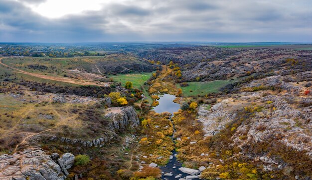 Un arroyo fluye en el Cañón Aktovsky, Ucrania. Árboles otoñales y grandes cantos rodados de piedra alrededor.