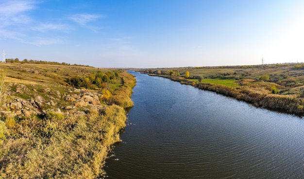 Un arroyo que fluye entre enormes piedras cubiertas de pequeñas plantas secas en la cálida luz del atardecer en la pintoresca Ucrania. Disparo de drone aéreo