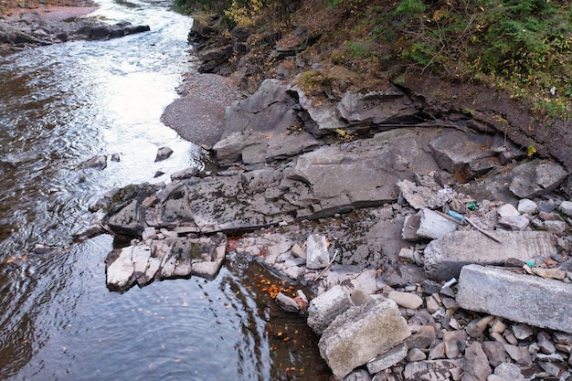 Arroyo del río que pasa por el pie de la montaña con bosque de otoño