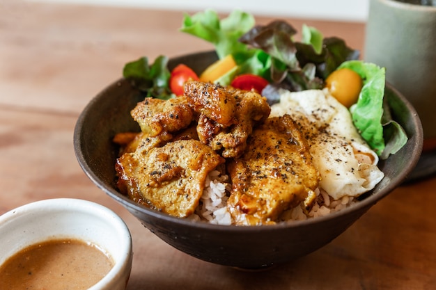 Arroz a vapor com frango satay e ovo frito servido com salada, incluindo carvalho verde e tomate. Servido com molho Satay.