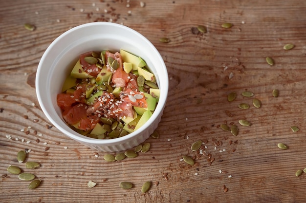 Arroz con aguacate y poke de salmón con semillas de sésamo de calabaza sobre un fondo de madera Espacio de copia de comida asiática