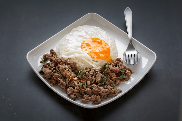 Arroz al vapor cubierto con albahaca, carne de res frita y huevo frito