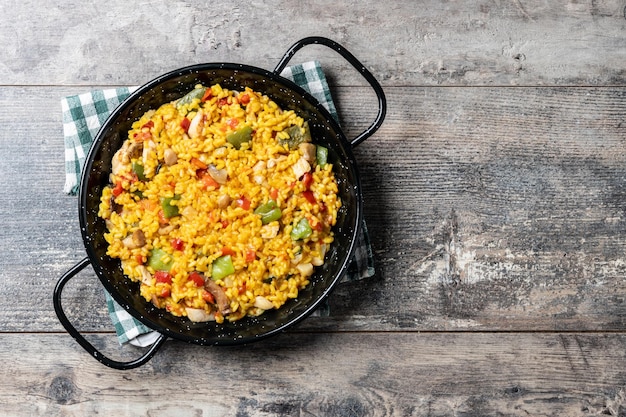 Arroz amarillo con pollo y verduras en una mesa de madera