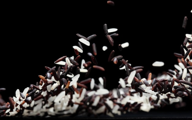 Arroz de arroz japonés volando explosión arroz de grano blanco berry caer abstracto volar hermosa semilla completa jazmín arroz de arroz salpicado en el aire objeto de comida fondo negro aislado enfoque selectivo borroso