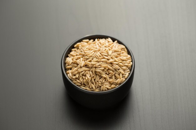 Foto arroz de avena en un pequeño cuenco negro en una mesa de madera negra