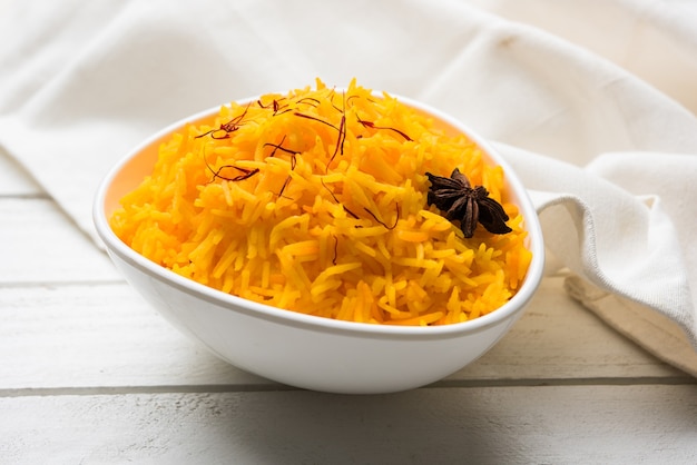 Arroz con azafrán o Kesar chawal o bhat, servido en un cuenco de cerámica blanca, enfoque selectivo