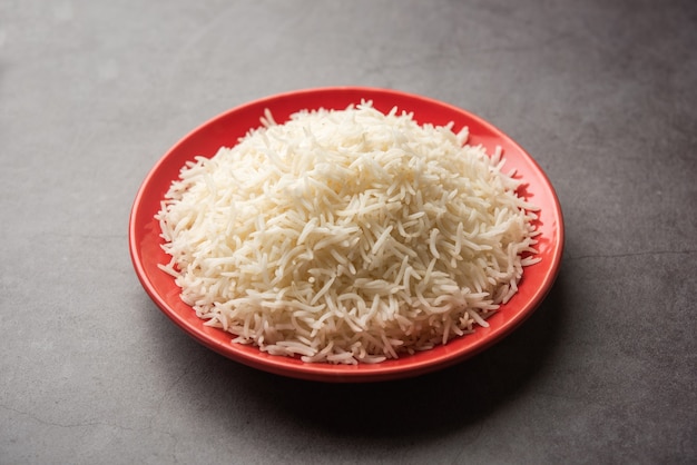 Arroz basmati blanco liso cocido en placa roja, enfoque selectivo