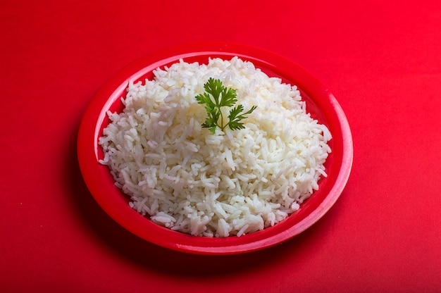 Foto arroz basmati blanco liso cocido en una placa roja sobre rojo