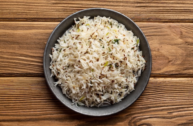 Arroz biryani cozido indiano com salada com cominho em fundo rústico de madeira. Guarnição ou acompanhamento indiano vegetariano saudável tradicional. Vista do topo