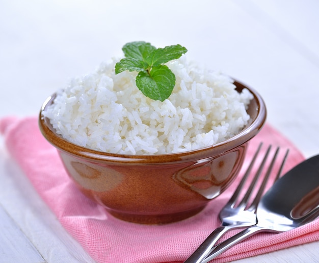 Arroz blanco cocido adornado con menta en un tazón de cerámica