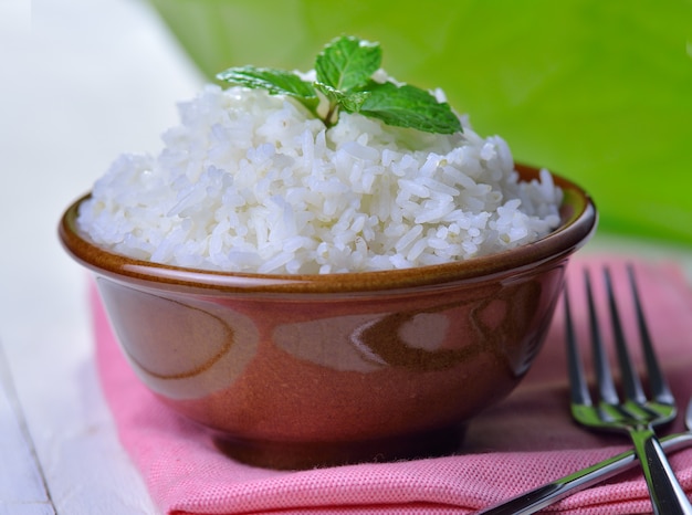 Arroz blanco cocido adornado con menta en un tazón de cerámica