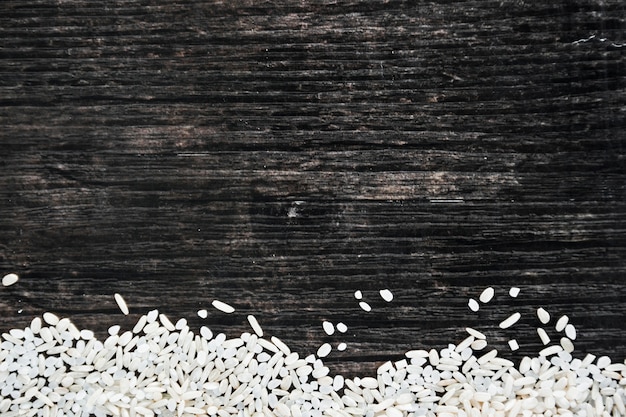 Arroz blanco crudo sobre fondo texturado de madera negro