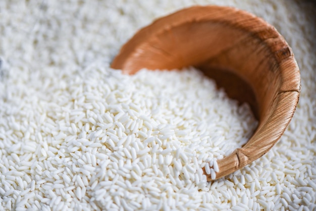 Arroz blanco de jazmín con cuenco de naturaleza en el saco de cosecha de arroz y conceptos de cocina de granos alimenticios