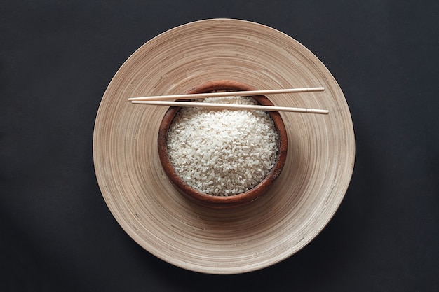 Arroz blanco en tazón de madera con palillos de madera