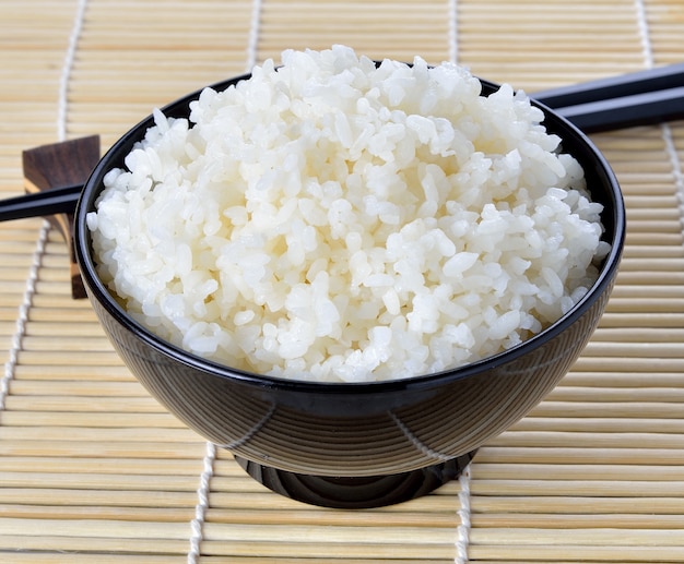 Arroz branco cozido no vapor em tigela redonda preta