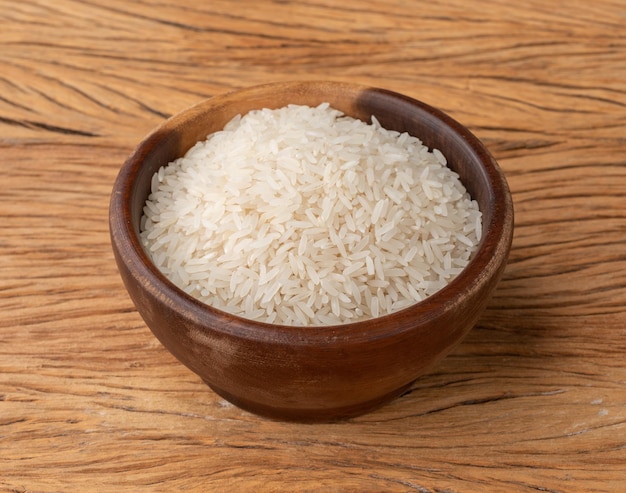 Arroz branco cru em uma tigela sobre a mesa de madeira