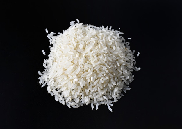 Foto arroz branco cru isolado em um fundo preto a maioria dos asiáticos ainda consome arroz diariamente