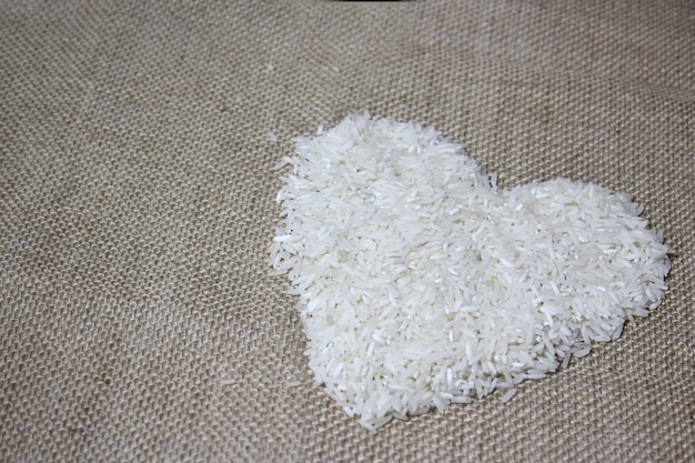 Arroz branco em forma de coração em tecido de juta de serapilheira Foco seletivo
