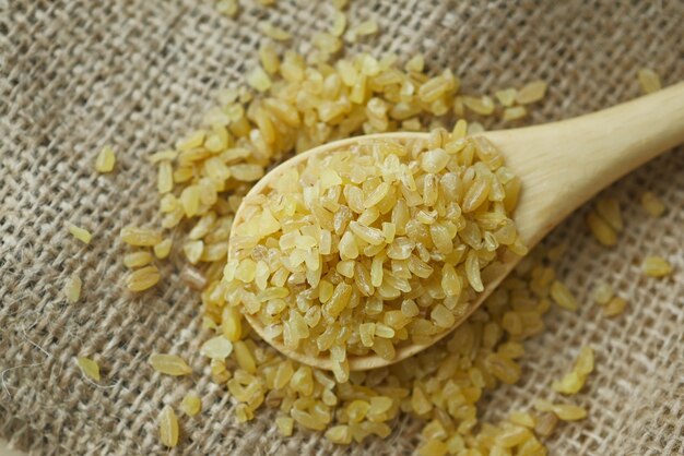 Arroz bulgur cru em colher de madeira.