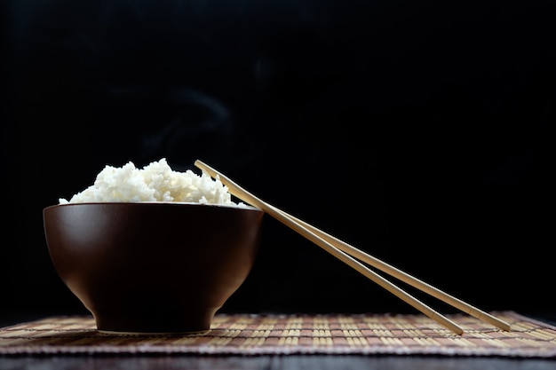 Arroz caliente en un tazón marrón con palillos al estilo japonés