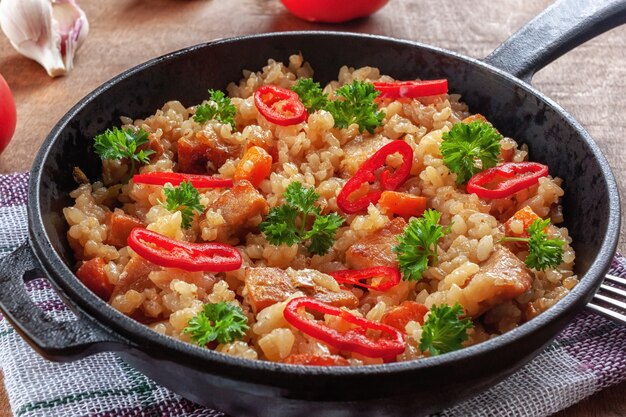 Arroz con carne, verduras y perejil en una sartén