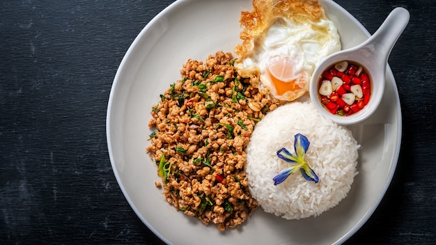 Arroz con cerdo salteado y albahaca sobre madera. comida tailandesa