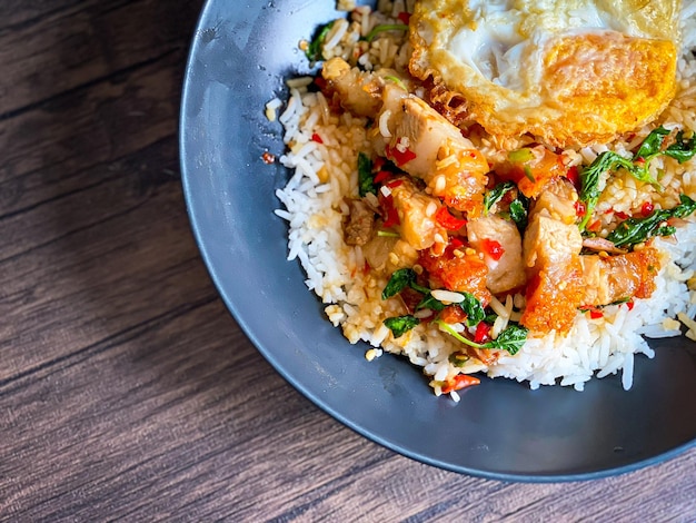 Foto arroz coberto com barriga de porco crocante com manjericão tailandês e ovo frito