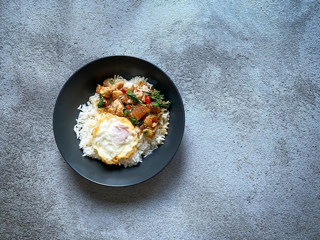 Foto arroz coberto com barriga de porco crocante com manjericão tailandês e ovo frito