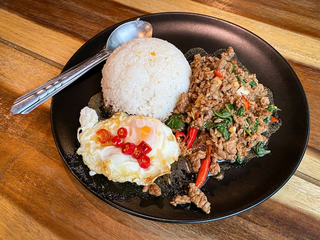 Arroz coberto com carne frita e manjericão com ovo frito na mesa