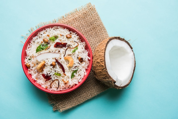 Arroz de coco - Receta del sur de la India con sobras de arroz basmati cocido, servido en un tazón rojo sobre fondo cambiante, enfoque selectivo