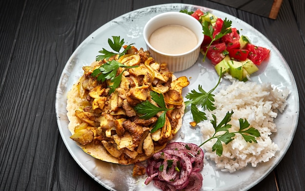 Arroz com carne, cogumelos, vegetais, pita e molho, sobre fundo preto