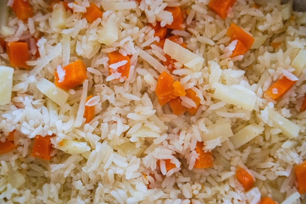 Foto arroz com cenoura e cebola numa frigideira vista de cima