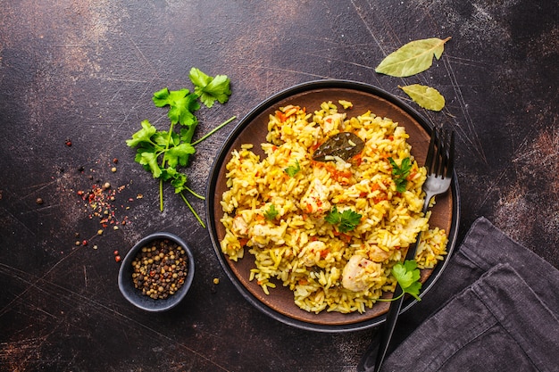 Arroz com galinha em uma placa preta em um fundo escuro, vista superior.