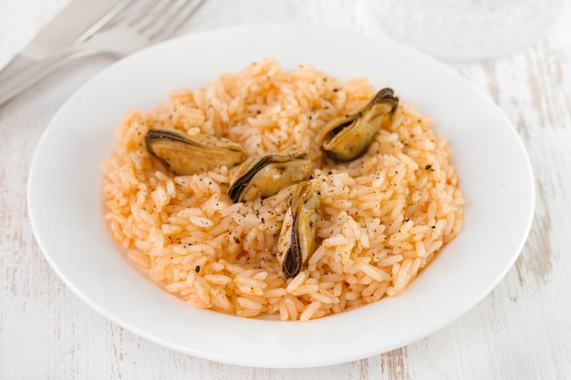 Arroz com mexilhões na chapa e copo de água