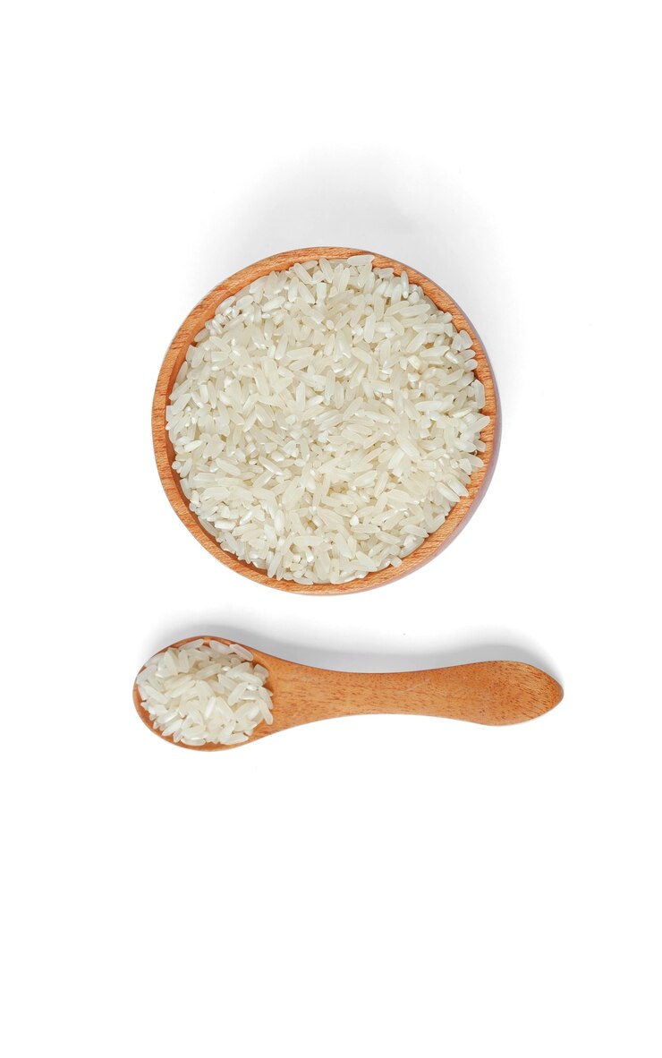 Foto arroz com tigela de madeira e colher de pau, isolado no fundo branco, vista superior