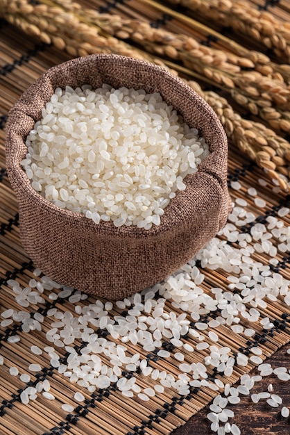 Arroz comestible molido pulido blanco crudo sobre fondo de mesa de madera en un recipiente, concepto de diseño orgánico.