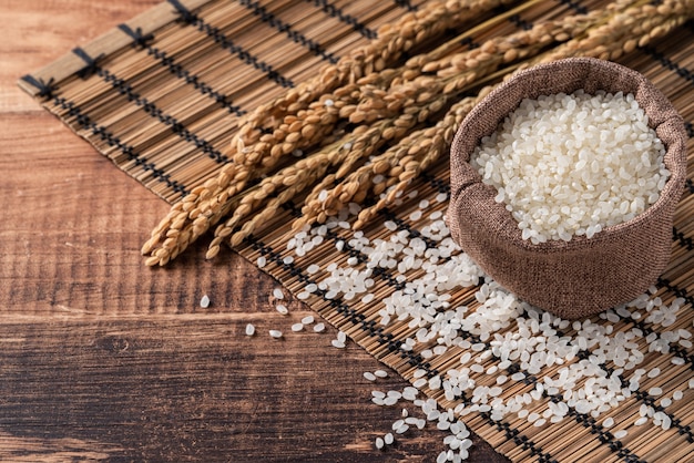 Arroz comestible molido pulido blanco crudo sobre fondo de mesa de madera en un recipiente, concepto de diseño orgánico.