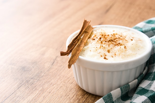 Arroz con leche oder Milchreis mit Zimt auf Holztisch