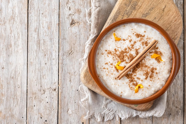 Arroz con leche Reispudding mit Zimt in einer Tonschüssel auf einem Holztisch