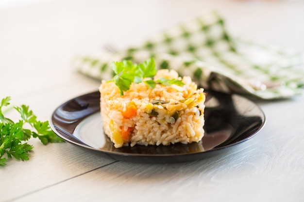 Arroz cozido com cenouras e legumes em um prato em uma mesa de madeira leve