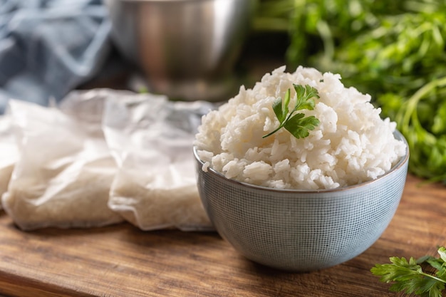 Arroz cozido em uma tigela com arroz cru em sacos de plástico