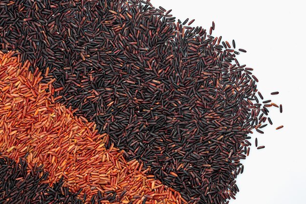 Arroz cru com duas fileiras de arroz preto e vermelho para o fundo branco isolado