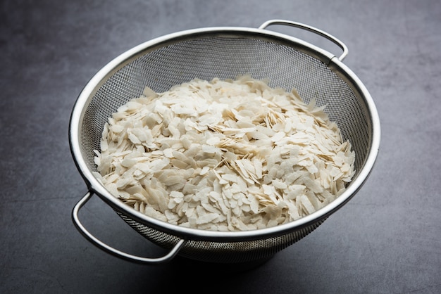 Arroz crudo aplanado o copos de arroz espesos o delgados para bocadillos Namkeen Chivda o Aloo Poha para desayuno indio, servido en un tazón