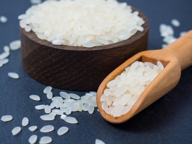 Arroz crudo blanco en un bol y un primer plano de una cuchara de madera