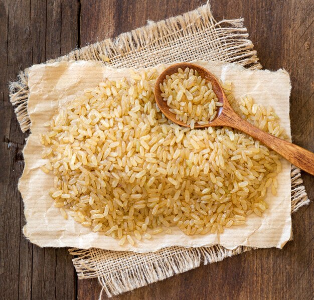 Arroz crudo con una cuchara en una mesa de madera