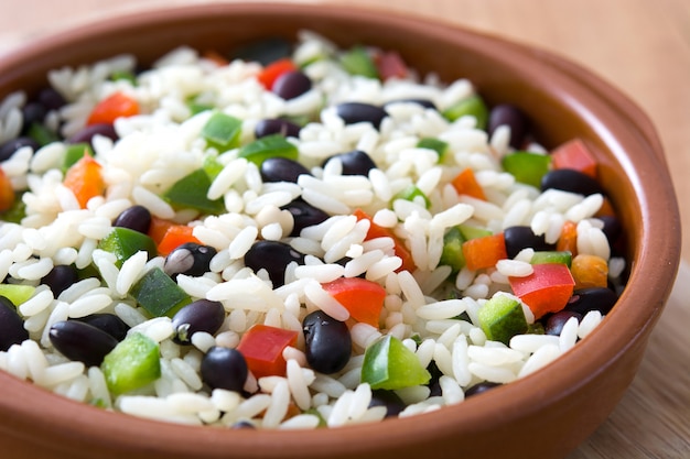 Arroz cubano tradicional, frijoles negros y pimienta en la mesa de madera