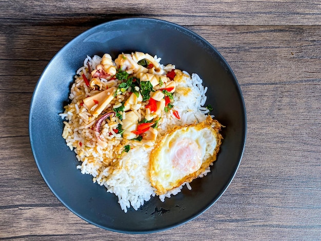 Arroz cubierto de calamares salteados y albahaca con huevo frito