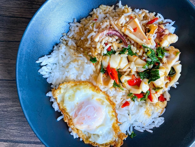 Foto arroz cubierto de calamares salteados y albahaca con huevo frito