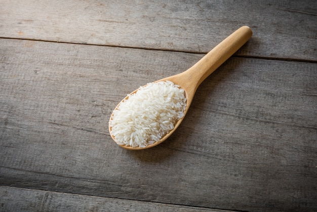 Arroz en cucharas de madera en el fondo de madera, naturaleza muerta